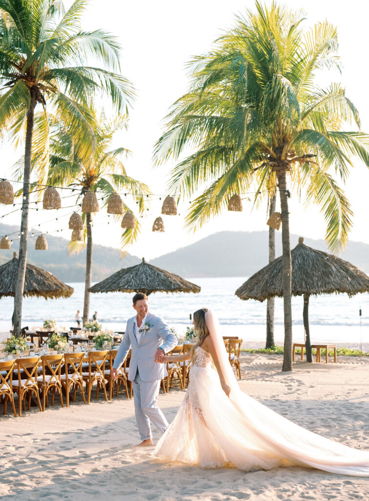 bride and groom holding hands in front of the beach